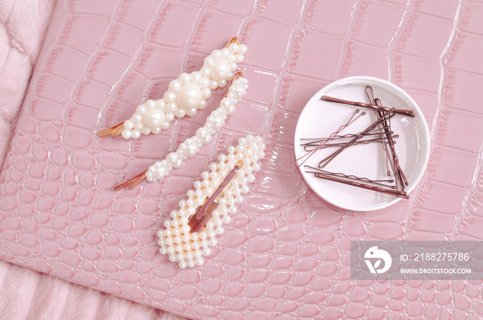 Set of pearl hairpins and elastic bands on pink background