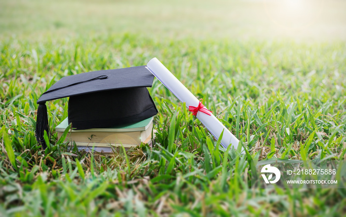 Closeup certificate paper and black cap on green grass spring time in the outdoor park. Education happy success achievement graduated celebrate graduate day concept panoramic background banner