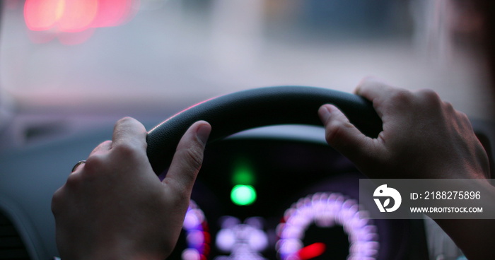 Hands holding car steering wheel waiting in red-light. Close-up person POV driving