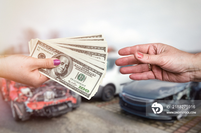 Macro focus on female hands with dollar upon crashed car