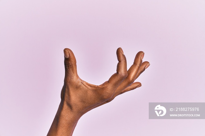 Arm and hand of black middle age woman over pink isolated background picking and taking invisible thing, holding object with fingers showing space