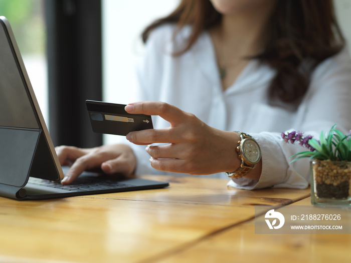 Female hand holding credit card while online paying on digital tablet