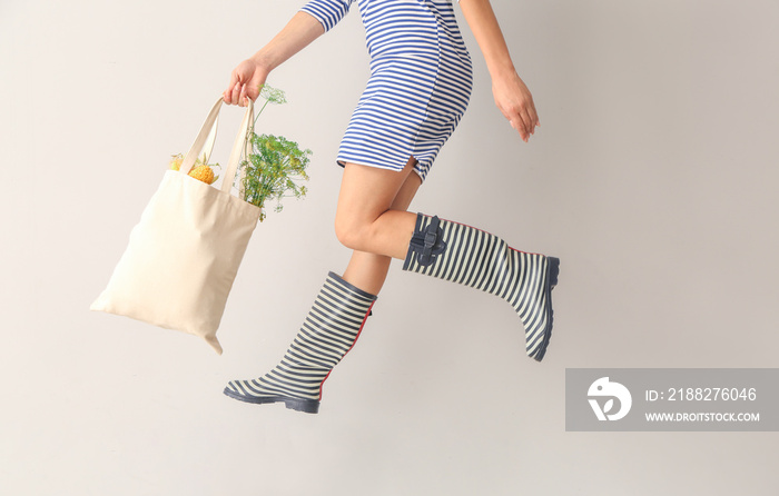 Jumping woman with eco bag on light background