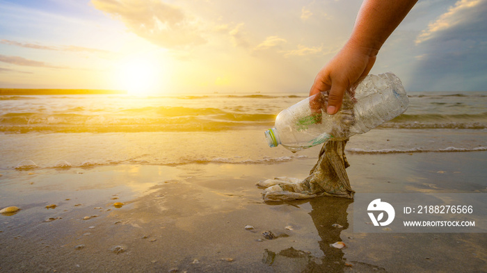 The hand is picking up trash on the beach, the idea of environmental conservation