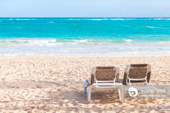 Two vacant sunloungers are on sandy beach