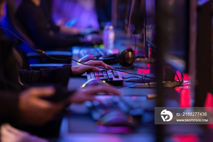 Young men sit at computer gaming setups and playing an online game