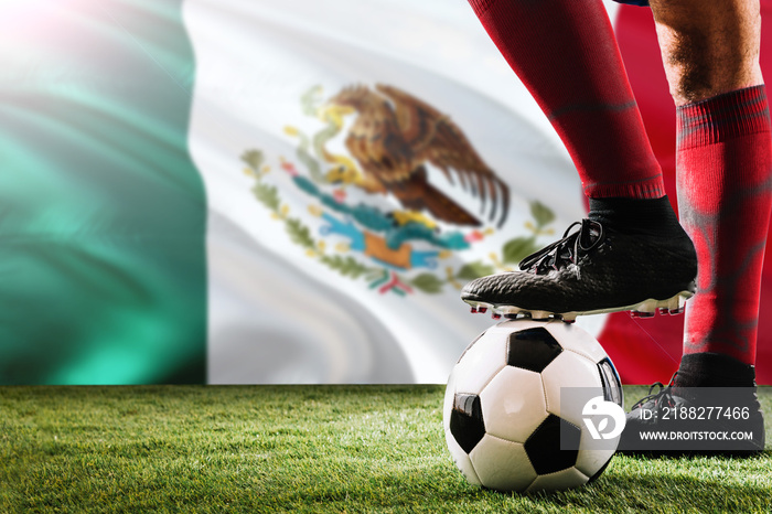 Close up legs of Mexico football team player in red socks, shoes on soccer ball at the free kick or penalty spot playing on grass.