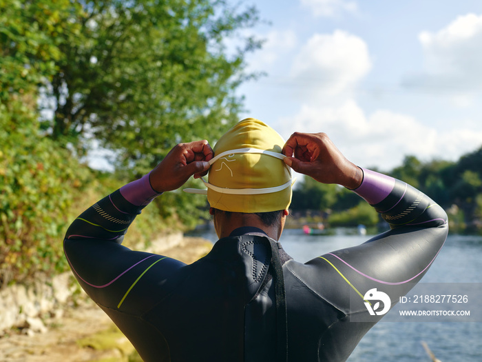 Woman in wetsuit putting on swimming cap