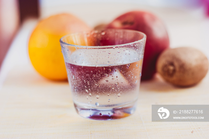 Glass of water on fruits background