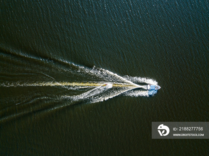 Aerial drone view. Wake surfing behind a boat on the river on a sunny summer day.