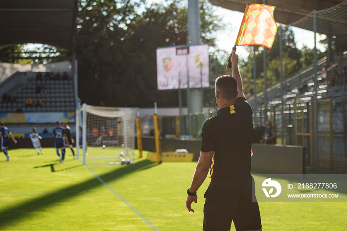 Touchline referee with reised flag during the soccer match.