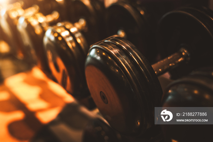 Black steel dumbbell set. Close up of dumbbells on rack in sport fitness center background. Workout training and fitness gym concept. Healthy and well being concept. Sport equipment and tool theme.