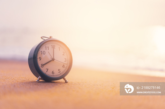 Clock on sand beach with smooth wave background.