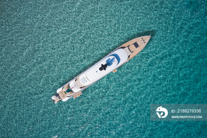 White big yacht for a billionaire anchored aerial view. Mega yacht on blue water aerial view. Modern big white yacht on transparent water top view.