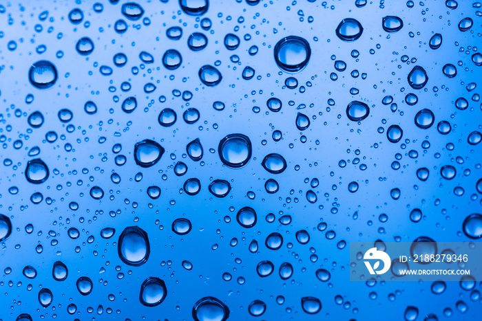 Water drops on glass window blue background after the rain in the autumn fall