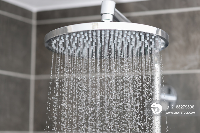 Close-up of water streaming from rain shower head in bathroom. Sale of plumbing concept.