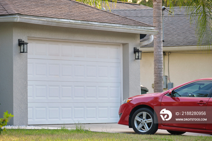 Vehicle parked in front of wide garage double door on paved driveway of typical contemporary american home