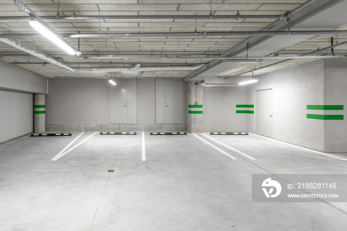 Empty public underground parking lot or garage interior with concrete stripe painted columns and signs