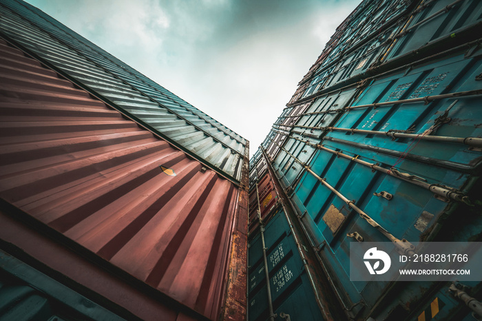 Cargo container for overseas shipping on high stack look up from ground . Logistics supply chain management and international goods export concept .