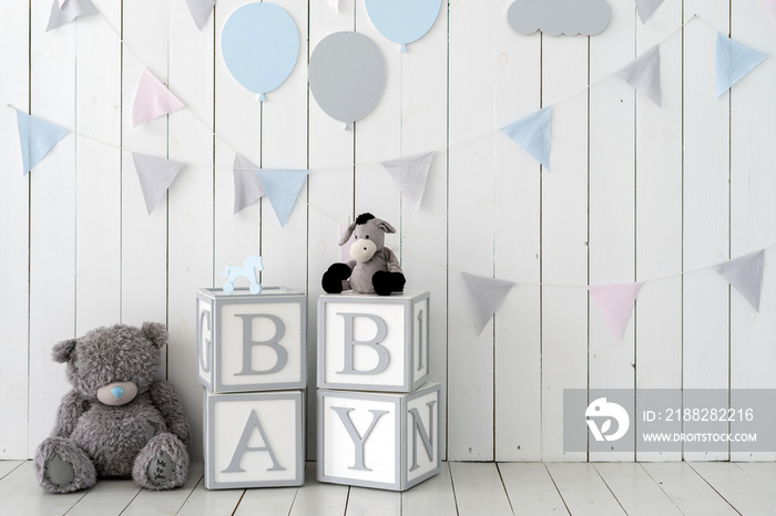 Word baby on wooden cubes near toys and decorated wall