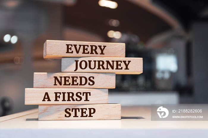 Wooden blocks with words ’Every journey needs a first step’.