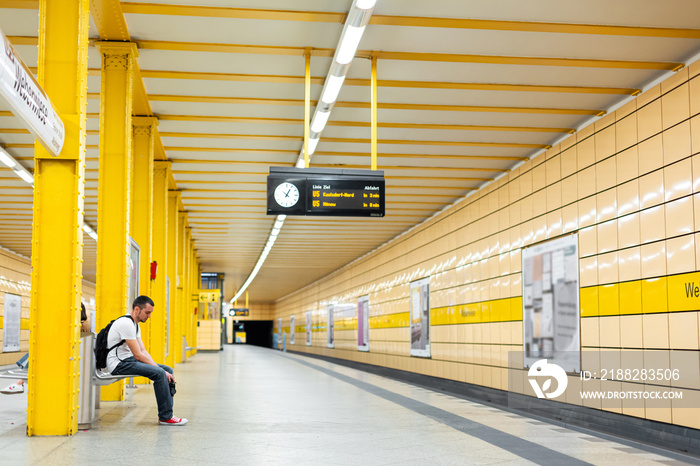 The guy is alone waiting for the train at the subway station