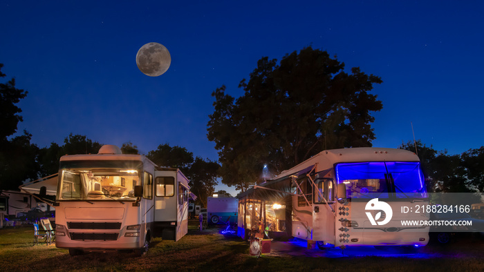 Rv camping under the moon with motorhomes lights on