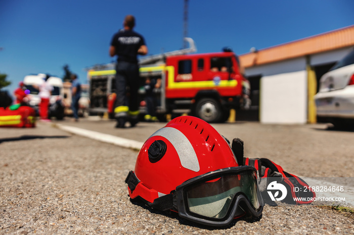 Closeup of protective helmet. In background are firemen and fire truck.