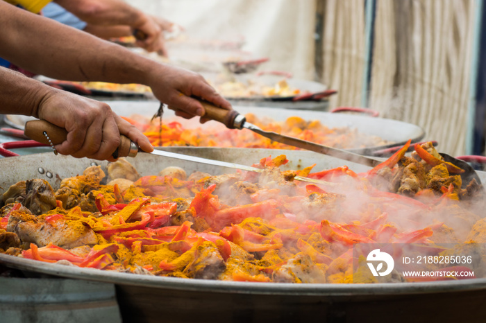 The giant paella. Stirring of cooking ingredients in large frying pans.