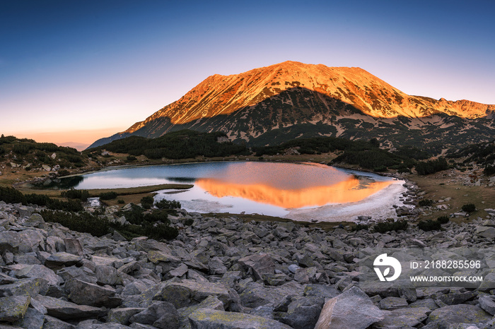 Pirin mountain national park. Panoramic colorful sunset view of Todorka peak with reflection in Muratovo lake, Bulgaria