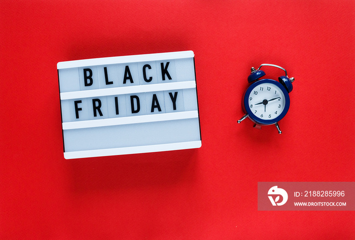 Creative flat lay composition sale text on lightbox, blue alarm clock on red background with copy space. Template Cyber Monday sale mockup