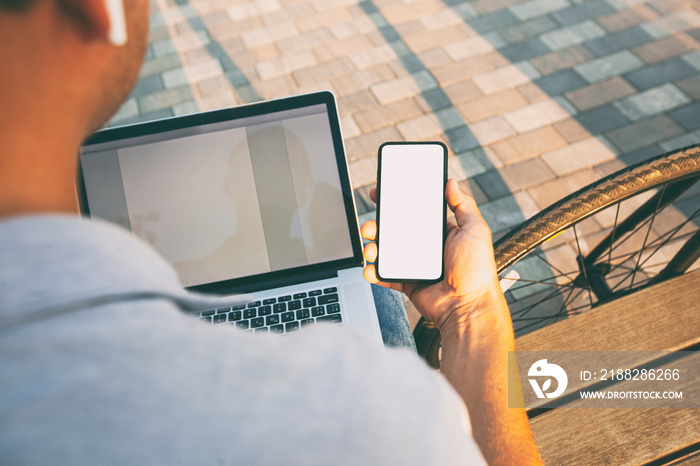 The guy sitting on the bench with bicycle and laptop and showing the phone with blank white screen