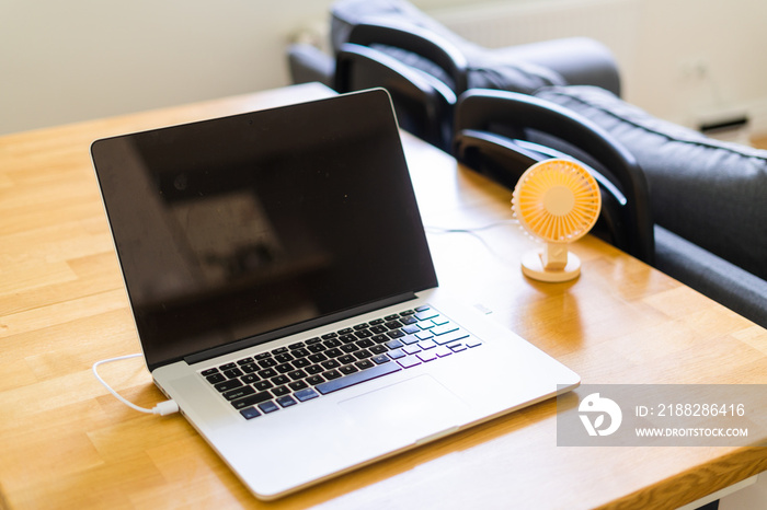 Mini usb fan near laptop. Summer office day. Mini portable cooler