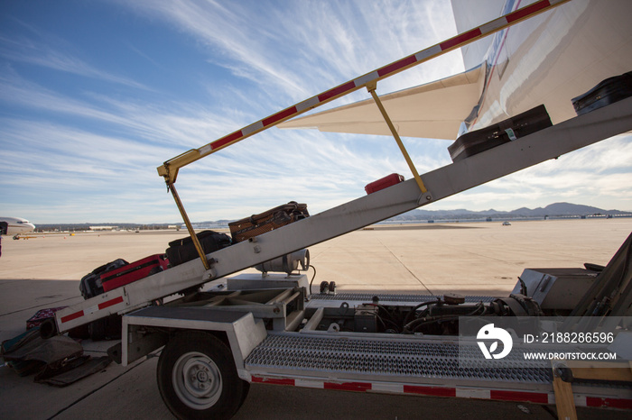 Luggage is being loaded in a passenger plane on a tarmac. Beautiful day at the airport with dramatic clouds.