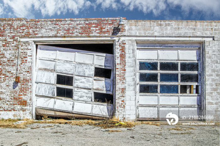 Aftermath of tornado - Commercial garage doors in vintage brick building - one is wrecked and mangled while one is still intact