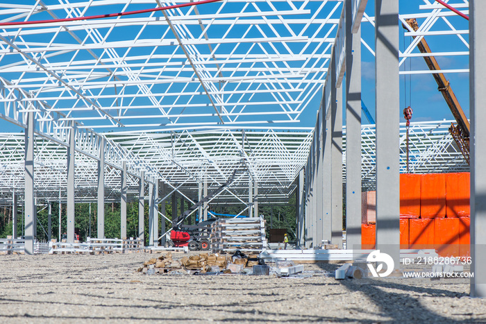 Industrial construction site of new commercial shopping mall. Reinforced concrete piles foundation for the building. Ongoing framing, construction of factory. Construction workers and trucks