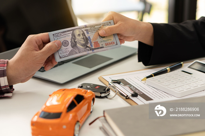 Car trading and insurance concepts in protection The buyer of the new car makes a contract with the car salesman at the showroom on the day of pick-up and hands the cash to the dealer in the office.