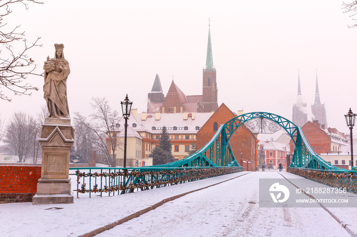 Tumski Bridge and Island with Cathedral of St. John and church of the Holy Cross and St. Bartholomew in the snowy overcast winter day in Wroclaw, Poland