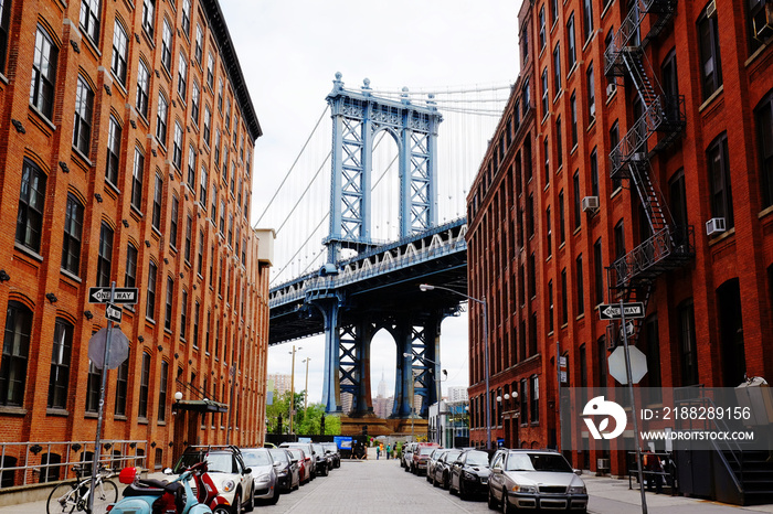 Manhattan bridge seen from a red brick buildings in Brooklyn street in perspective, New York, USA. Beautiful classic apartments in New York City. Beautiful american street. Famous view.