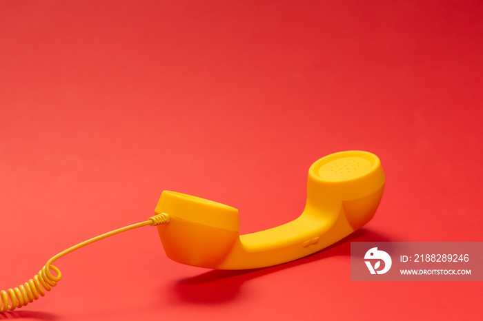 Yellow handset on red background. Copy space.