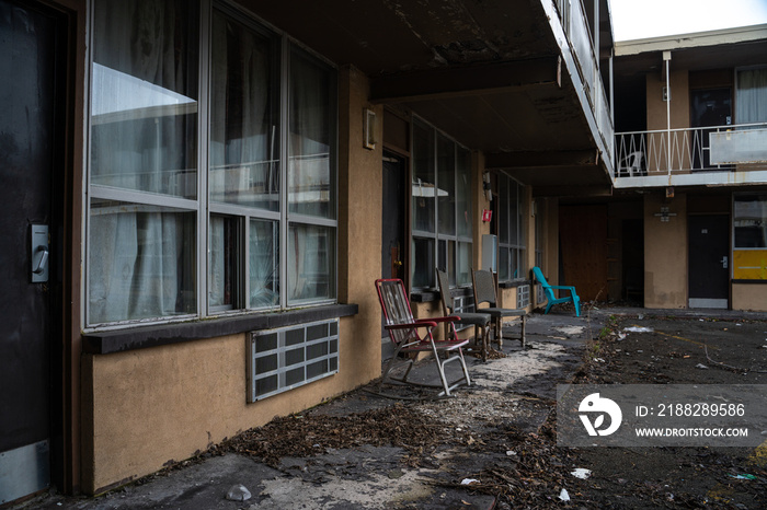 old abandoned motel with chairs in the front and dirty and vandalized environment