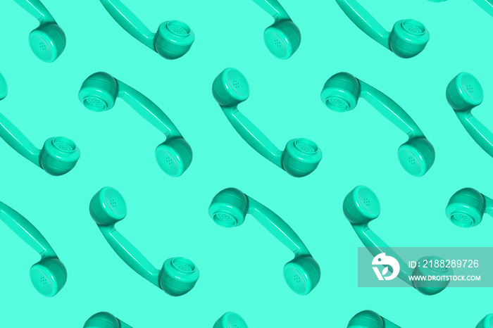 Pattern made from neo mint colored handset of a telephone on green mint background.