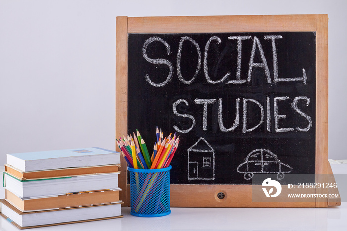 Blackboard with pencil cup and stack of books. Social studies concept.