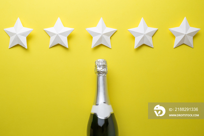 Top quality champagne wine abstract made of bottle and origami stars isolated on yellow.