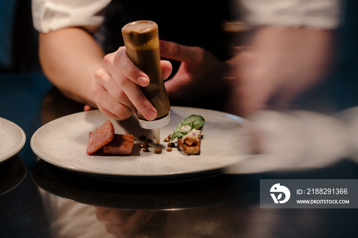 Close up of a chef’s hand cooking and preparing fine dining meals. Food prepping in the kitchen.