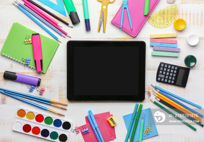 Set of school supplies with tablet computer on white wooden background