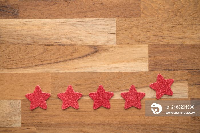 Red glitter five stars shape put on wooden table background. Services rating customer experience, satisfaction, and feedback score concept. Customer evaluation for product or service improvement.