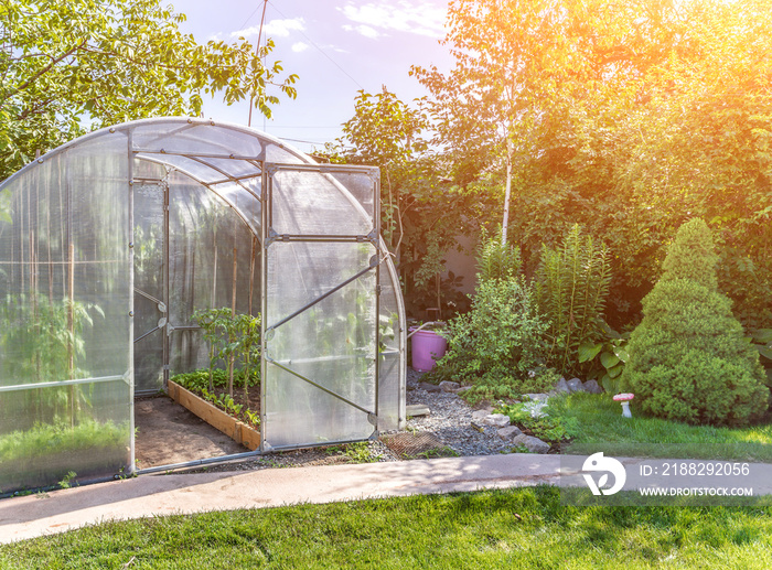 arched small greenhouse on private backyard with sun flare