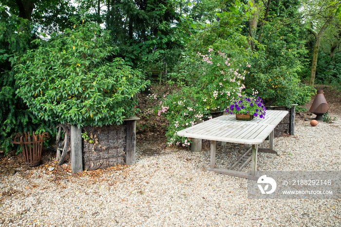 a place in a garden with a garden table and green plants and flowers