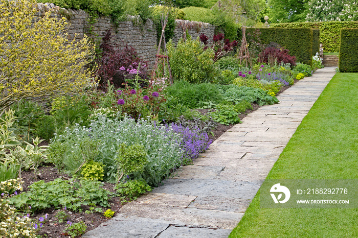 Stone flag path in front of a herbaceous border at an English country garden